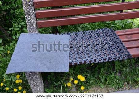 Carpet fabric doormats and openwork rubber mat doormat - cleaning , drying on the bench Royalty-Free Stock Photo #2272172157