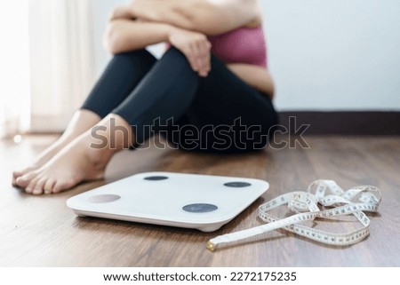 Obese Woman with fat upset bored of dieting Weight loss fail  Fat diet and scale sad asian woman on weight scale at home weight control. Royalty-Free Stock Photo #2272175235