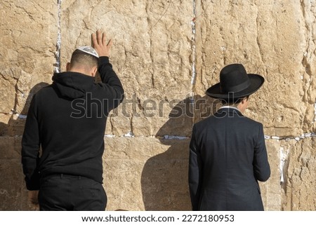 Back view of Jewish men wearing hat and yarmulke while facing Wailing Wall located in Jerusalem during sunny morning Royalty-Free Stock Photo #2272180953