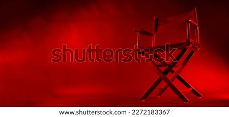 Black Director chair use in video production or cinema industry in red light color with black background.

