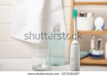 Electronic ultrasonic toothbrush, mouthwash, floss, tongue cleaner and toothpaste on white wooden background. Items for dental care and caries prevention in the bathroom. Dentistry concept. Copy space