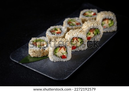 Maki rolls california with rice and avocado, cucumber, with spicy sauce. Appetizing vegan dish on a black background. Sushi spring rolls asian dish for street food menu.
