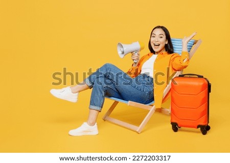 Young excited woman wear summer clothes sit in deckchair scream in megaphone isolated on plain yellow background. Tourist travel abroad in free spare time rest getaway. Air flight trip journey concept Royalty-Free Stock Photo #2272203317