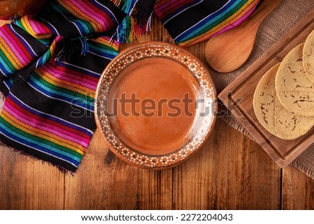 Cooking background with empty mud dish, mexican typical fabric on rustic wooden table. Table top view with copy space. Royalty-Free Stock Photo #2272204043