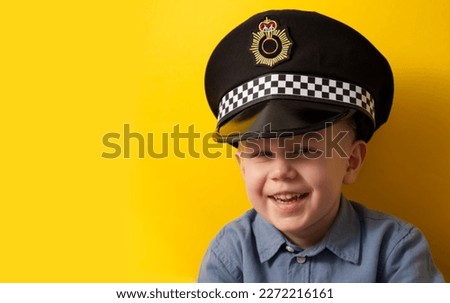 Cute boy in a cap of a policeman laughs on a yellow background. High quality photo