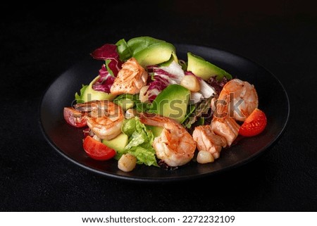 Salad with egg, fresh vegetables, cucumber, tiger shrimp and grated parmesan cheese. Fish diet dish seasoned with olive oil and spices. On a beautiful plate on a black isolated background.