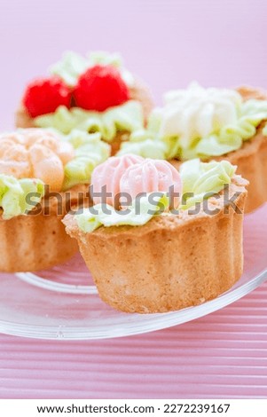Group of cupcakes on a plate with a pink background.