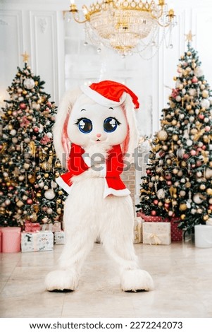 a bunny doll in a red santa claus costume in a room with Christmas trees. the concept of holidays and entertainment for children. carnival costumes and actors. Father Frost.