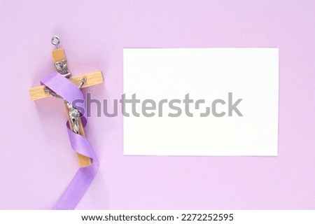 Christian religious wooden cross crucifix with violet ribbon on purple background. Catholic religion symbol. Good Friday, Lent Season, Palm Sunday, Ash Wednesday and Holy Week concept. Copy space