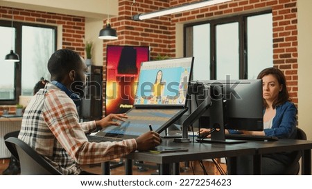 African american employee retouching professional photos, using touchscreen display and stylus pen. Image retoucher with graphic tablet using editing software to retouch picture in agency office.