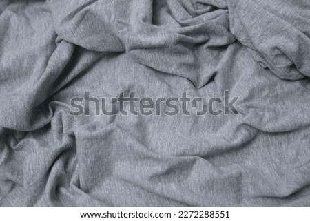 textured detail of the gray fabric with irregularly creased, folded or wavy patterns. used as a cover or abstract background