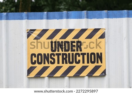 yellow under construction sign with white backgruond at park