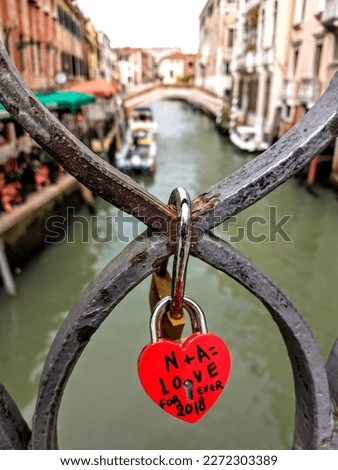 RED LOCKED PADLOCK ON A VENICE BRIDGE, PROOF OF ETERNAL LOVE AND UNION. Royalty-Free Stock Photo #2272303389