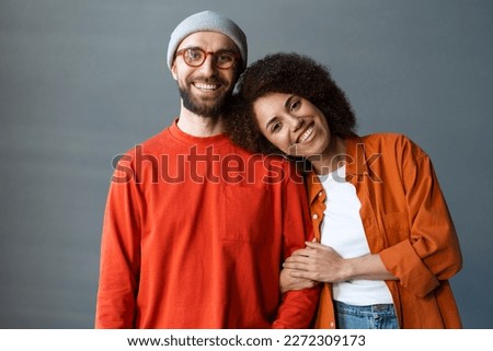 Happy stylish romantic couple embracing,  looking at camera standing together at new home. Portrait of smiling attractive confident best friends wearing colorful clothing. Love, relationship concept 