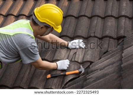 Worker man replace tile of the old roof. Repair roof concept. Royalty-Free Stock Photo #2272325493