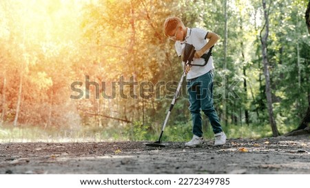 a boy with a metal detector is looking for treasure in the forest. High quality photo