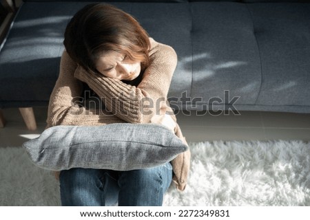 Depressed woman sitting alone in living room caused of sadness or broken heart. Depression is a form of highly negative thinking towards oneself, others and life. Royalty-Free Stock Photo #2272349831