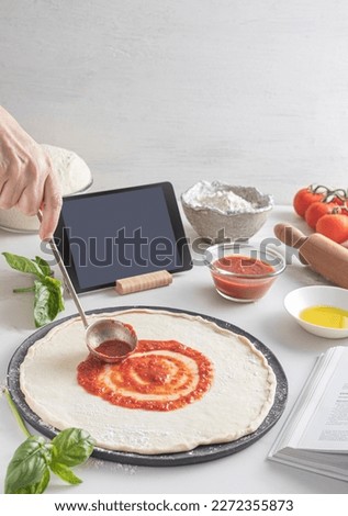 Raw dough for pizza with ingredient: tomato sauce, dough, mozzarella, tomatoes, basil, olive oil, spices served on rustic wooden table