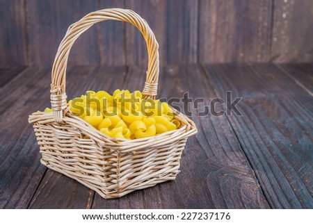 Raw pasta on basket on  wooden background - process old dark style picture
