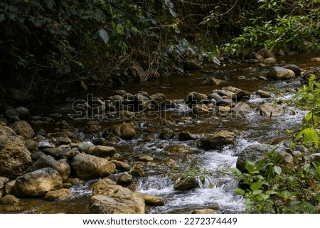 shallow river water with rocks around it, picture taken from an angle above during the day