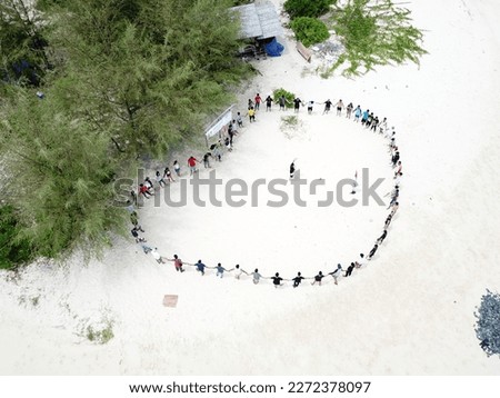 Group of people playing at the small tropical island above aerial view ( Tinalapu Island, Luwuk Banggai, Central Sulawesi, Indonesia).  