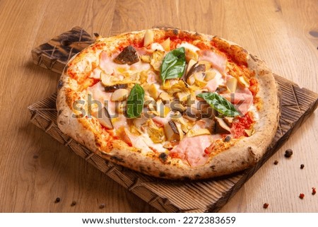 Capricciosa pizza with cheese, bacon, tomatoes, mushrooms and basil, italian meal. Baked neapolitan pizza with artichokes served on wooden board.