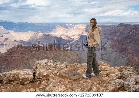 Portrait of a smiling young blonde girl with a vintage photo camera on the precipice of the Grand Canyon