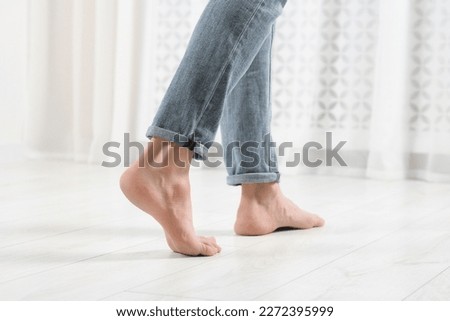 Barefoot woman walking on white parquet at home, closeup. Heated floor Royalty-Free Stock Photo #2272395999
