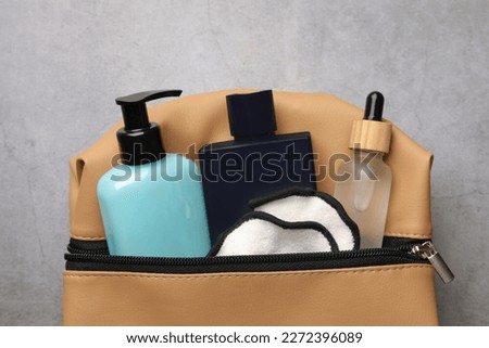 Preparation for spa. Compact toiletry bag with different cosmetic products on grey textured background, top view Royalty-Free Stock Photo #2272396089