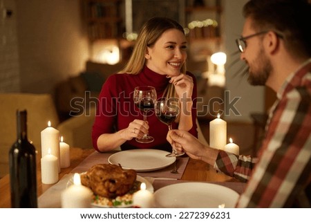 Beautiful couple having romantic dinner with candles and red wine at home Royalty-Free Stock Photo #2272396231