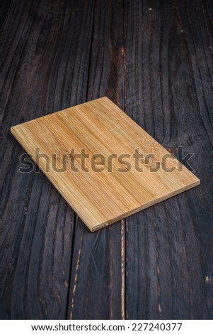 Cutting board on wooden background - old style picture process