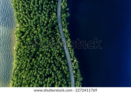 Aerial view of road in green woods and blue lakes water in summer Finland Royalty-Free Stock Photo #2272411769