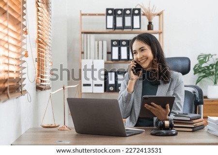 Female lawyer works in office or court, checks clients contracts, Calling by phone. Asian successful business lady, statuette of Themis, goddess of justice. legal advice online. Royalty-Free Stock Photo #2272413531