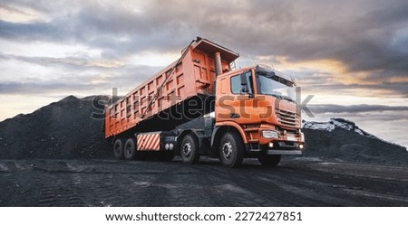 Large quarry dump truck. Dump truck carrying coal, sand and rock. Trucks moving on dirt country road in forest. Mining truck mining machinery to transport coal from open-pit. Transportation of mineral Royalty-Free Stock Photo #2272427851