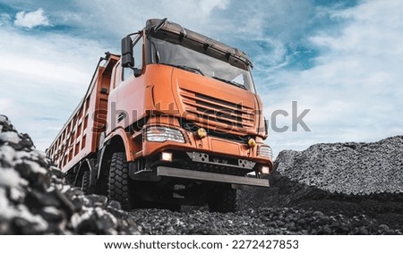 Large quarry dump truck. Dump truck carrying coal, sand and rock. Trucks moving on dirt country road in forest. Mining truck mining machinery to transport coal from open-pit. Transportation of mineral Royalty-Free Stock Photo #2272427853