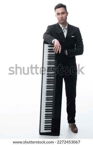 Studio portrait of a man playing at piano and smiling isolated on white background