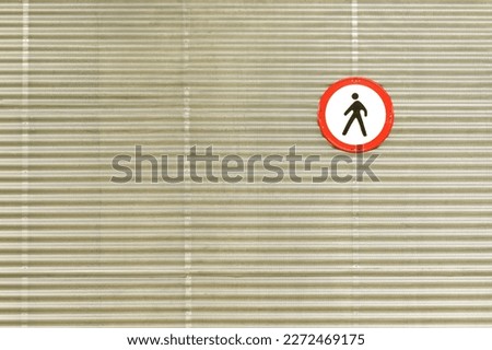 sign prohibiting the passage of pedestrians in a parking lot on a homogeneous metal wall