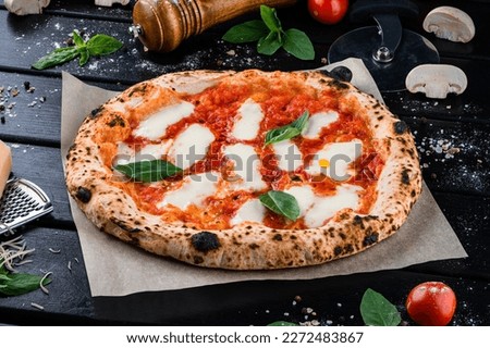 Neapolitan pizza with spices, tomatoes and cheese mozzarella on dark background. Pizza with mozzarella, tomato sauce, spinach on a thick dough. Royalty-Free Stock Photo #2272483867