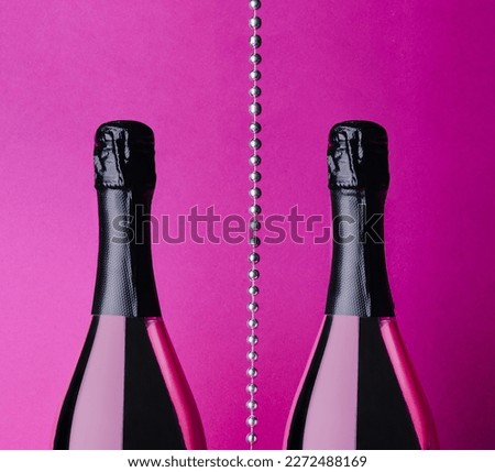 two champagne bottles on pink background