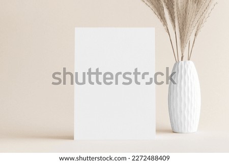 White invitation card mockup with a pampas decoration on the soft yellow background. 5x7 ratio, similar to A6, A5.