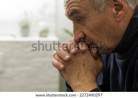Please, Lord. Nervous worried aged Caucasian man praying on couch at home. Stressed white European senior citizen sitting on sofa, begging for forgiveness or asking God for help in difficult situation Royalty-Free Stock Photo #2272490297