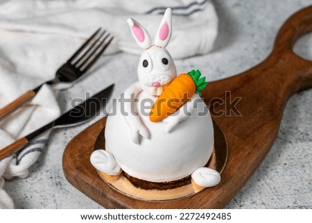 Specially designed bunny shaped cake. Cake on gray wooden table and Easter Bunny