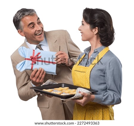 Vintage husband giving a gift to his beautiful wife, she is holding home made cookies