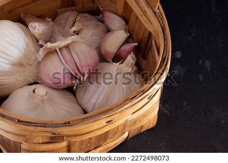 Garlic and garlic cloves into a basket made of chestnut wood and isolated on a black background. Natural antibiotic