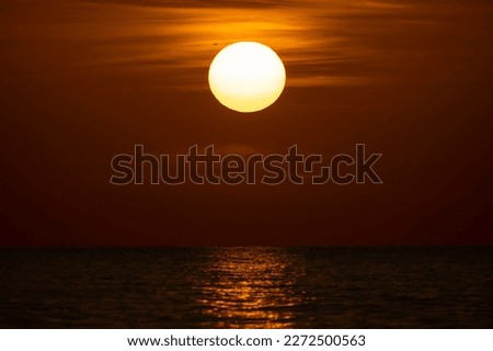 Ocean sunset. Big white sun on dramatic bright sky background, soft evening horizont over sea dark water Royalty-Free Stock Photo #2272500563