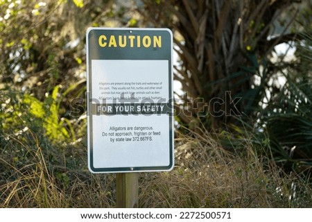 Alligators warning sign in Florida state park about caution and safety during trail walk