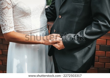 Close-up photo of the hands of the bride and groom, decorated with wedding rings. The beauty of their intertwined fingers. Rings on the hand of the bride and groom