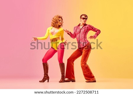 Rhythm and swing. Young stylish emotional man and woman, professional dancers in retro style clothes dancing disco dance over pink-yellow background. 1970s, 1980s fashion, music concept Royalty-Free Stock Photo #2272508711