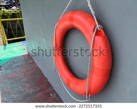 Red life buoy hanging on a blue wall in a aqua park. Help and support concept.