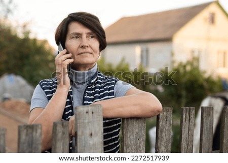 Mature woman standing relaxed near fence talking Royalty-Free Stock Photo #2272517939